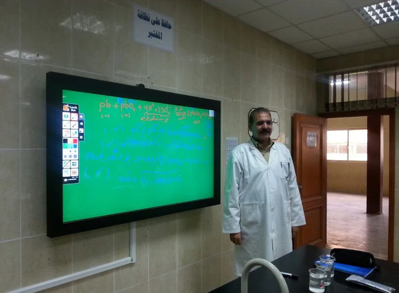Dr. Ahmed Aldiasty أمام سبورة المختبر أثناء شرح تفاعل كيميائي